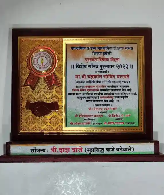 The plaque is titled (Vishisht Norvad Puraskar 2023) and recognizes an individual named (Ma. Shri. Chandrakant Narayan Waghmare).The plaque includes a handshake graphic, symbolizing partnership or achievement, and contains detailing the award's significance and the contributions of the recipient. At the bottom, there is a nameplate that reads (Saujanya: Shri. Dada Waje), indicating the sponsor or organizer of the award. The overall design is elegant and conveys a sense of honor and recognition.